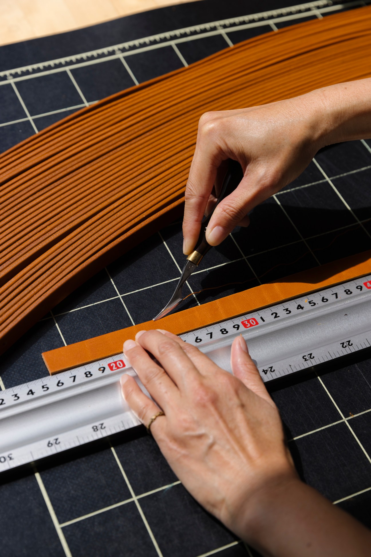 Hands measuring fabric or material with a measuring tool in a workshop setting