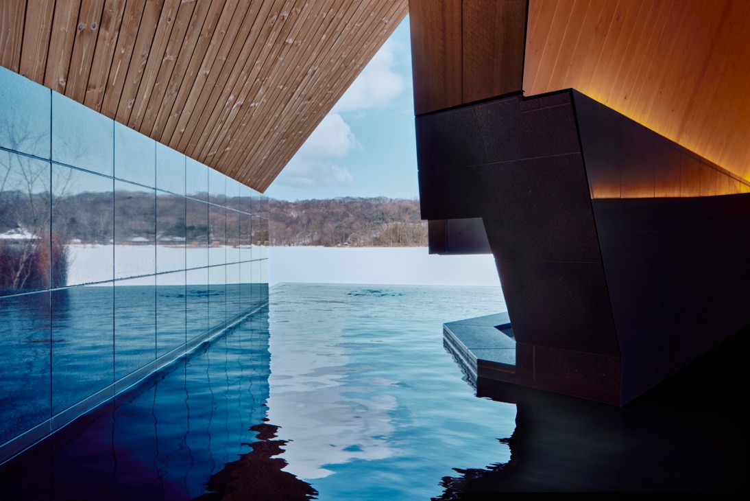 Interior view of triangular-shaped hot spring bath with wooden walls and warm lighting