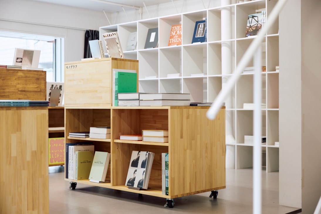 Modern wooden shelving units with geometric compartments displaying books and objects at Shinkenchiku Shoten