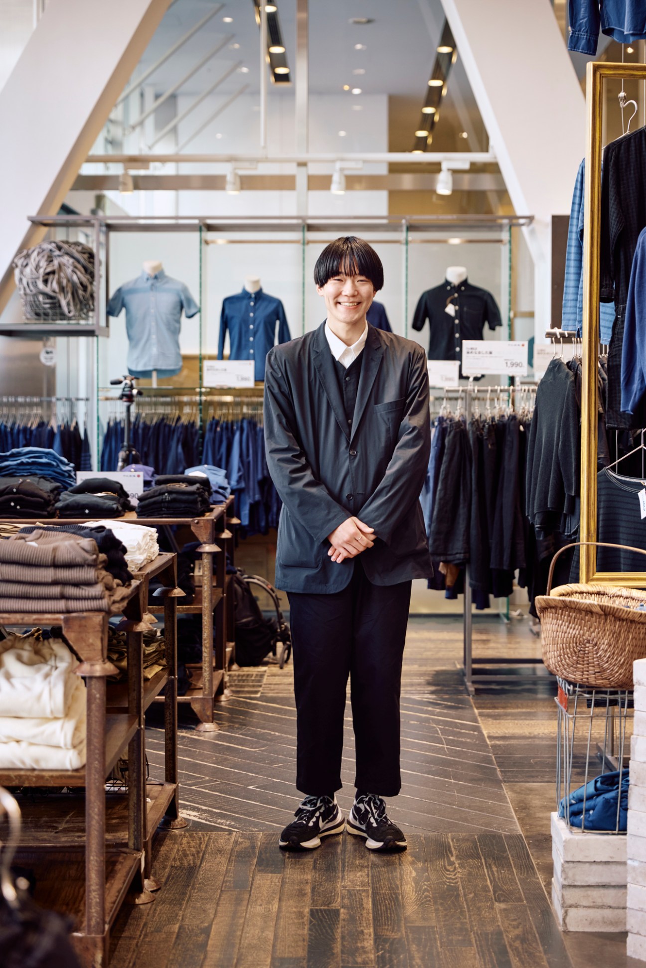 Smiling staff member in dark clothing standing in a modern retail store interior