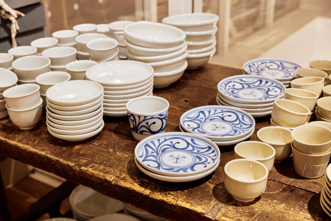 White ceramic bowls, cups and plates with blue decorative patterns displayed on wooden shelves