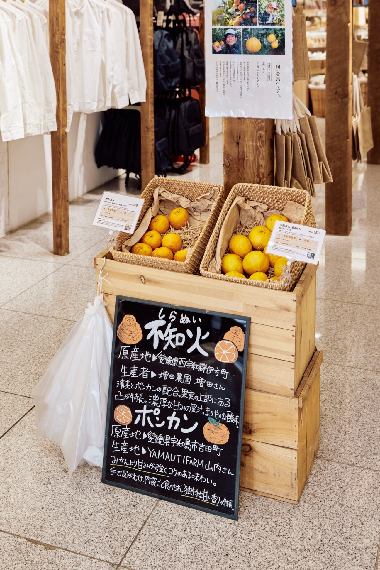 Citrus fruits displayed in woven baskets with Japanese signage on black board