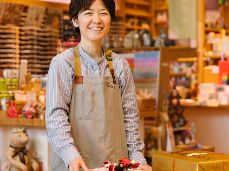 Sayaka Takagi smiling behind a counter with wrapped gifts at Itoya's Ginza store