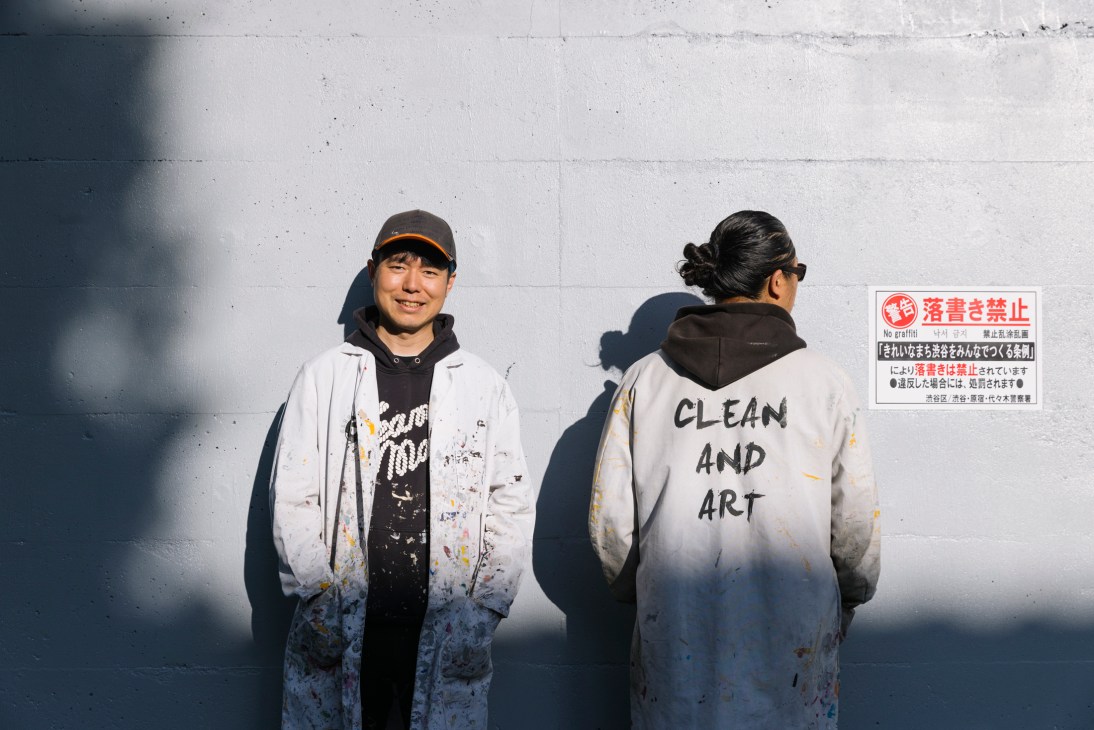 Ken Sobajima and Hisayoshi Yamauchi from Clean and Art in white lab coats standing against a wall in Tokyo