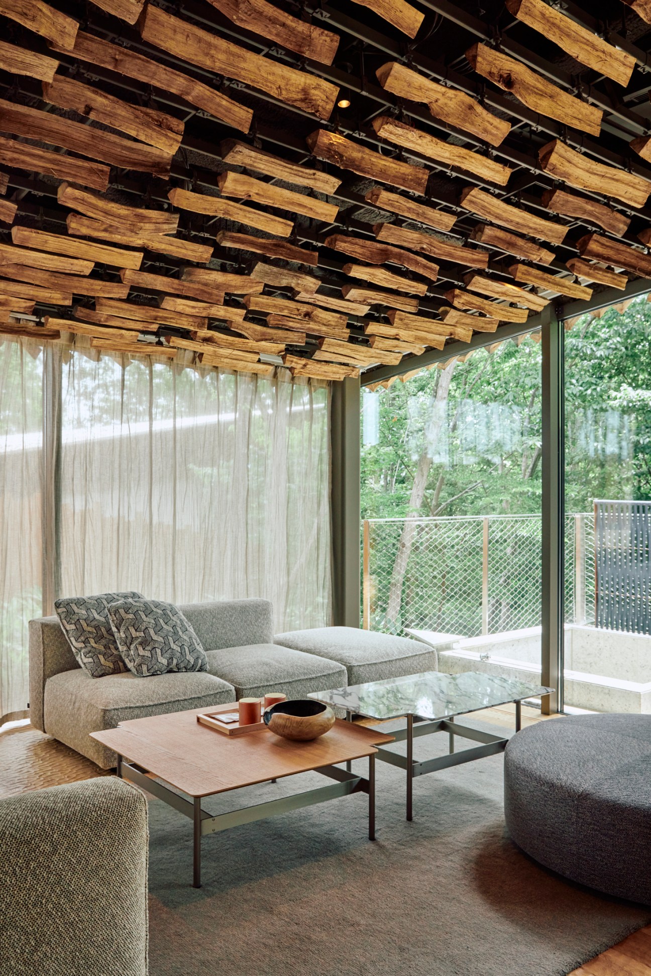 Modern living room with gray sectional sofa, wooden coffee table, and distinctive wooden ceiling installation
