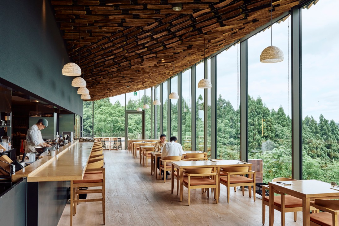 Modern restaurant interior of Seppo with wooden ceiling, large windows overlooking forest, and diners at wooden tables