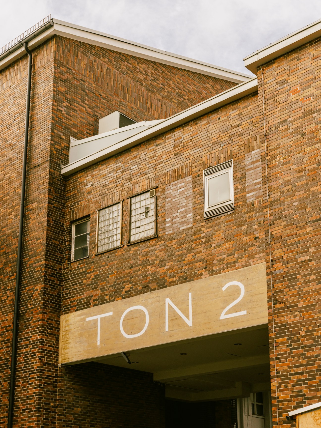 Brick building exterior with glass block windows and TON2 signage at Atelier Gardens film studio complex