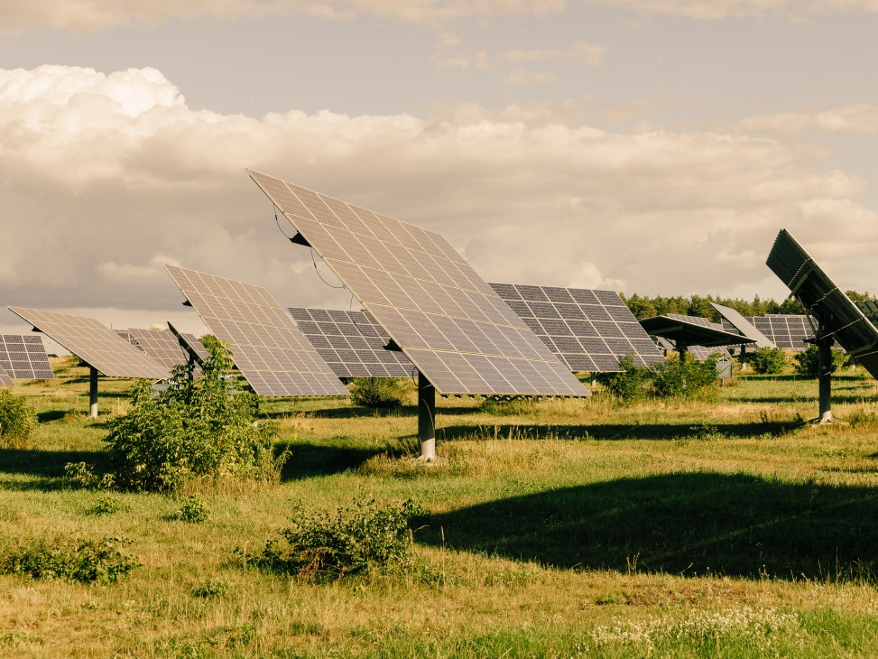 Solar panel trackers in a green field under cloudy sky in Feldheim, Germany.