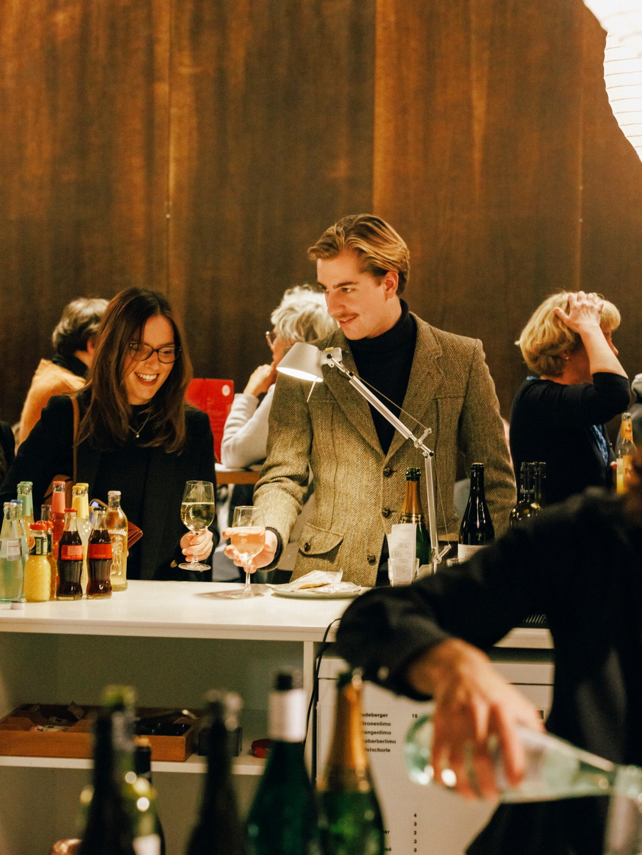 People socializing at a bar with drinks and golden curtains in the background at Deutsche Oper.