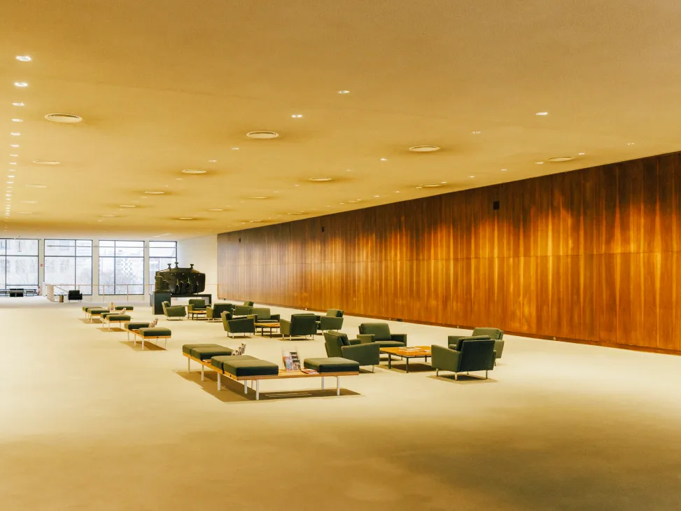 A spacious modernist lobby with minimalist mid-century furniture, warm wood paneling, and recessed ceiling lights at Deutsche Oper Berlin.