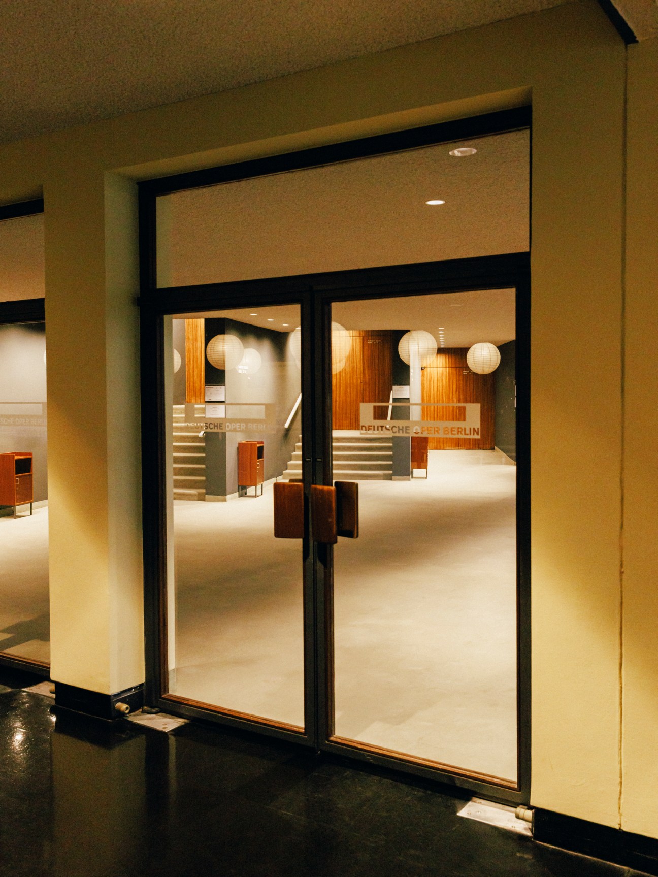 Deutsche Oper Berlin's modernist lobby with glass doors, paper lanterns, and minimalist furnishings.