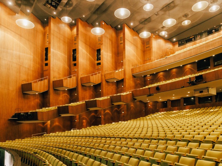 Interior view of Deutsche Oper's auditorium showing tiered seating and wood-paneled walls with modernist design