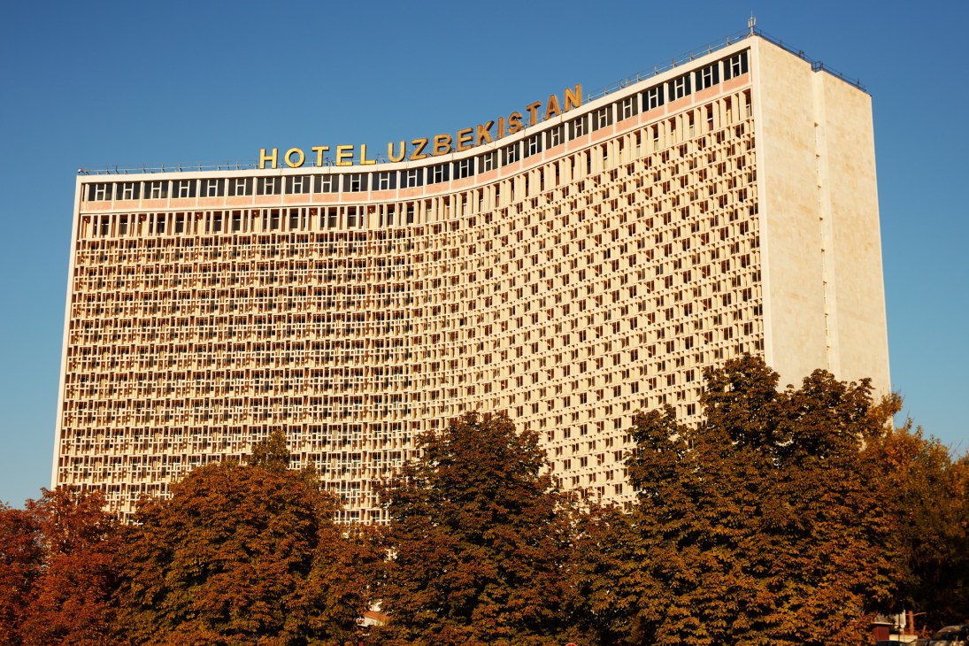 Hotel Uzbekistan brutalist concrete building with geometric facade rising above autumn trees