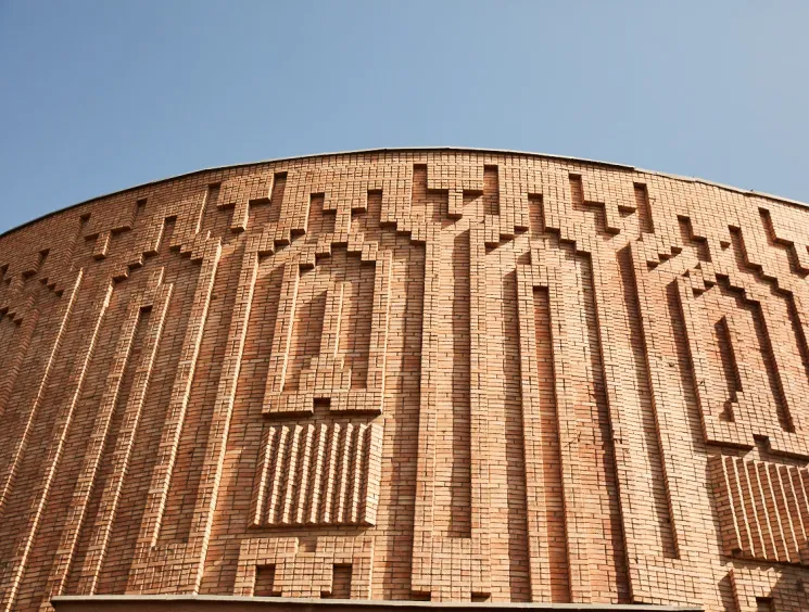 Curved brick building facade with intricate geometric relief patterns.
