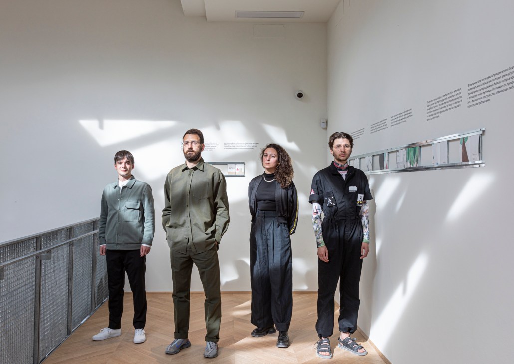 Four members of the Russia pavilion team standing in a bright gallery space with white walls and text displays.