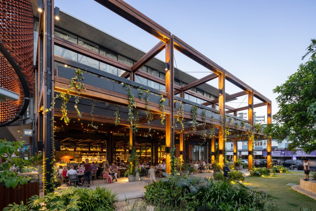 Modern restaurant with timber pergola, string lights, and outdoor dining area surrounded by landscaped gardens