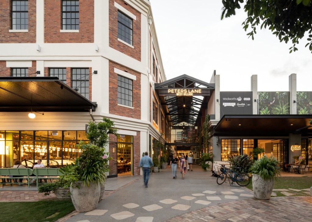 Pedestrians walking through Peters Lane covered walkway at West Village shopping precinct with stores and restaurants