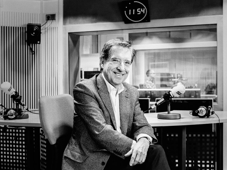 Iñaki Gabilondo, veteran Basque journalist, smiling at a radio studio desk with microphones and equipment.