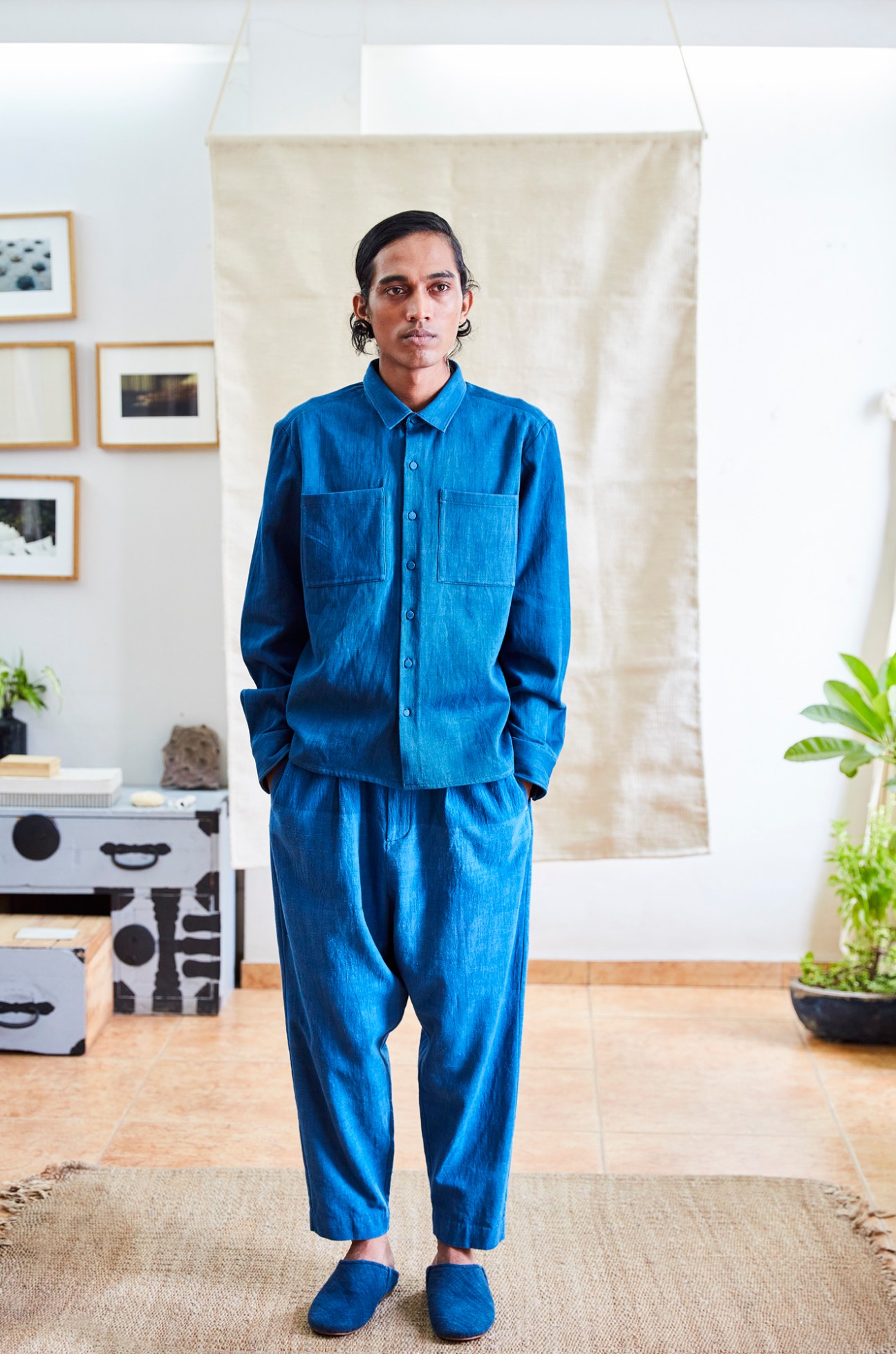 Person wearing blue linen shirt and matching pants in minimalist interior setting