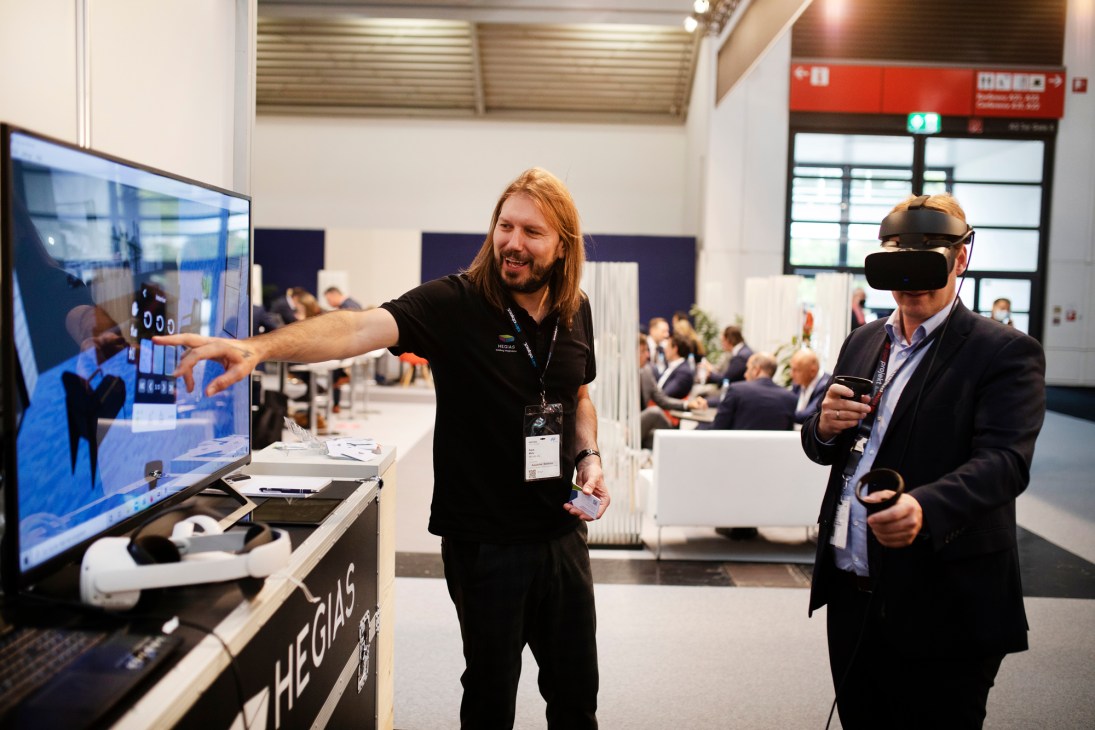 Patrik Marty of Hegias demonstrating virtual reality building technology to a visitor wearing VR headset
