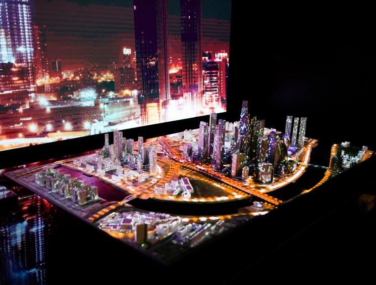 Illuminated architectural model of city development with miniature buildings and LED lighting displayed at exhibition