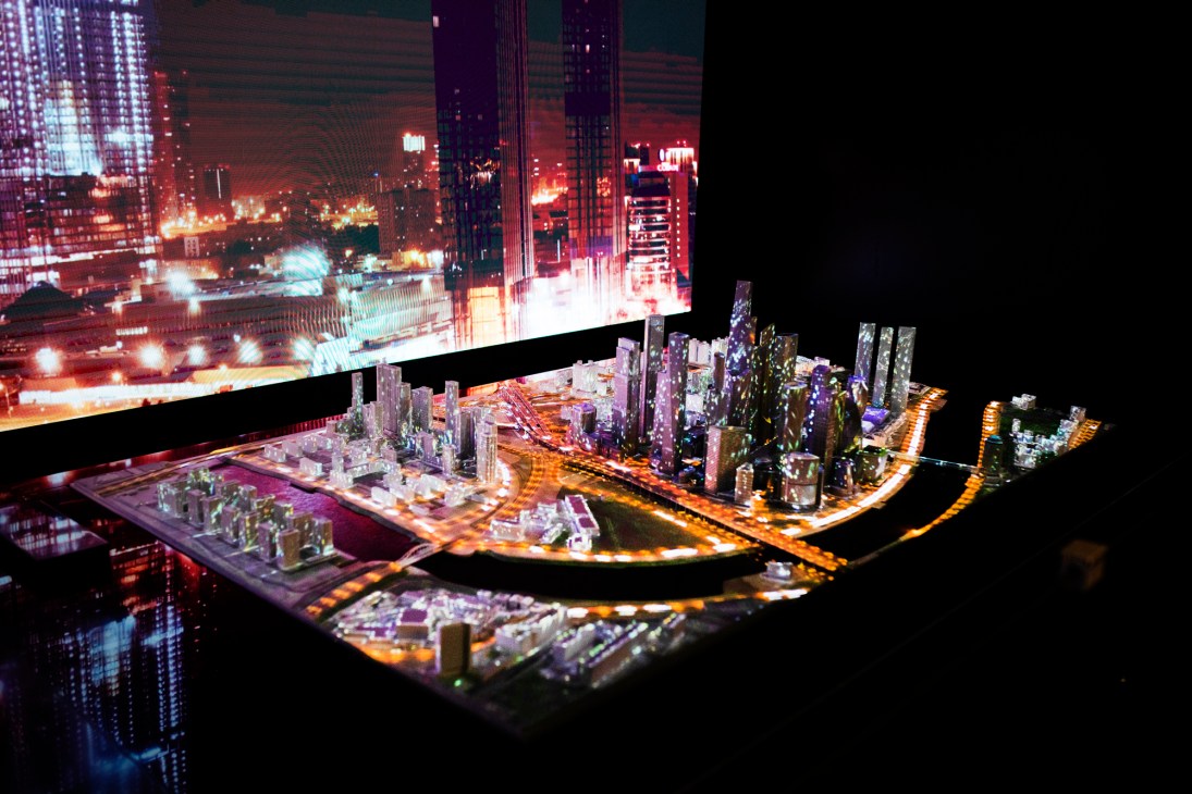 Illuminated architectural model of city development with miniature buildings and LED lighting displayed at exhibition