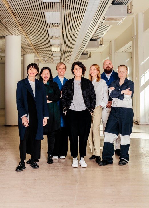Mirkku Kullberg and her team of seven people standing in a modern corridor at Glasshouse Helsinki.