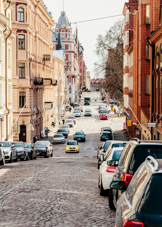 View down a Helsinki high street lined with colourful historic buildings and parked cars.
