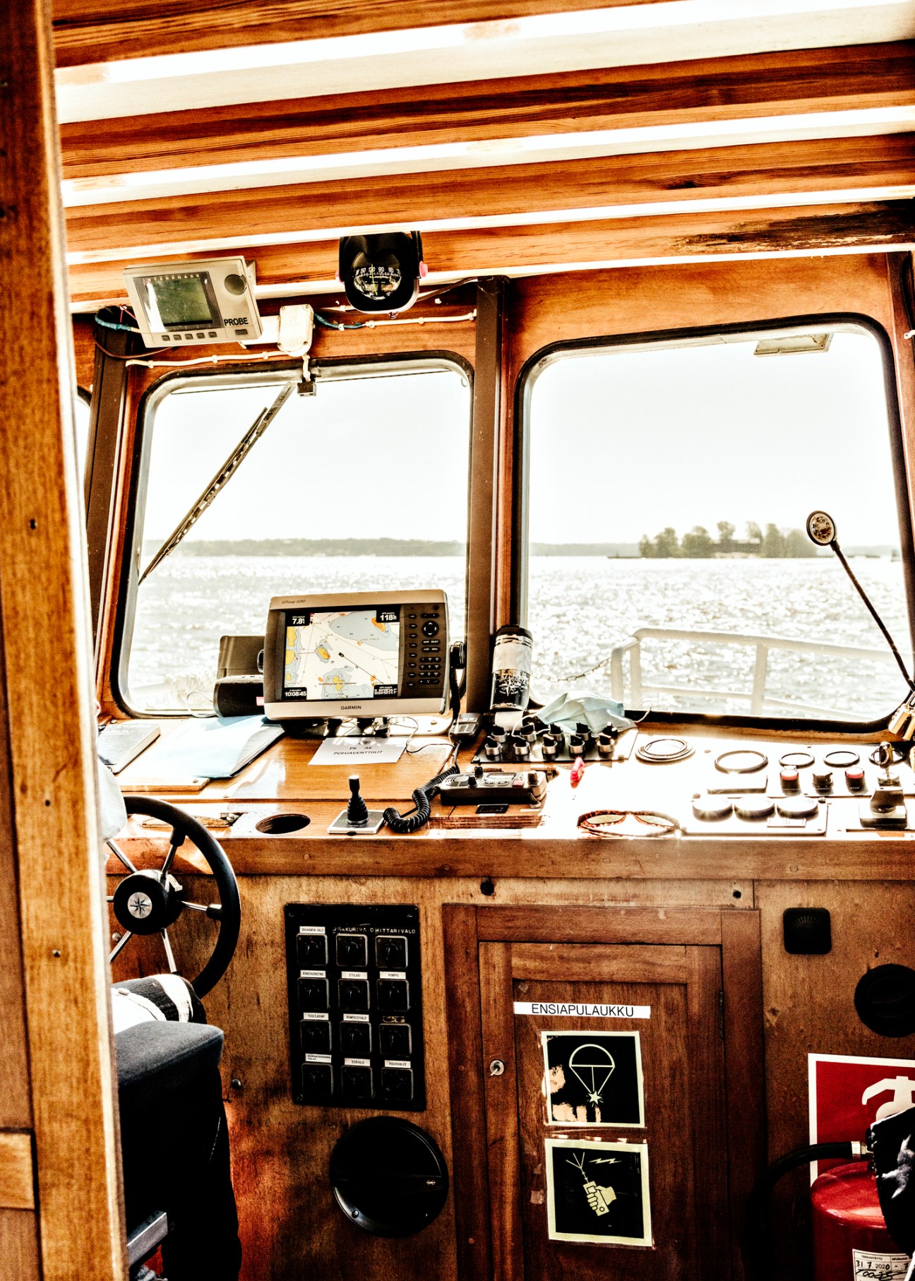 Interior of a ferry's captain cabin with wooden paneling, navigation equipment, and windows overlooking the Baltic Sea.