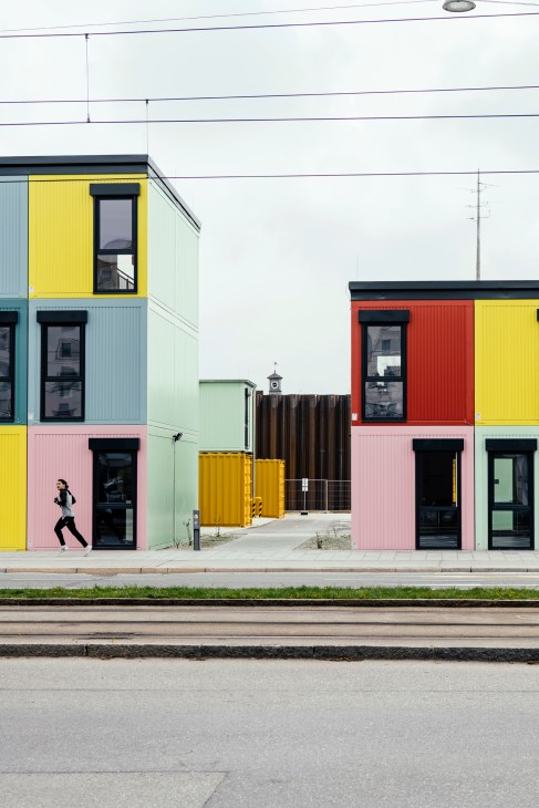 Colorful office buildings made from repurposed shipping containers with yellow, pink, red and green panels and black-framed windows.