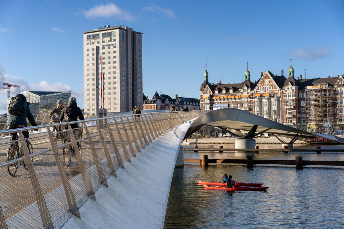 Modern curved pedestrian and cycle bridge with sleek metal design spanning across water