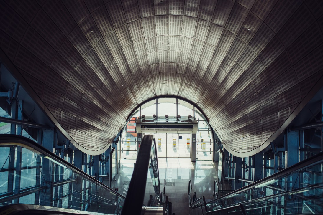 Interior view of a Dubai Metro station showing the distinctive arched ceiling and platform with escalators.