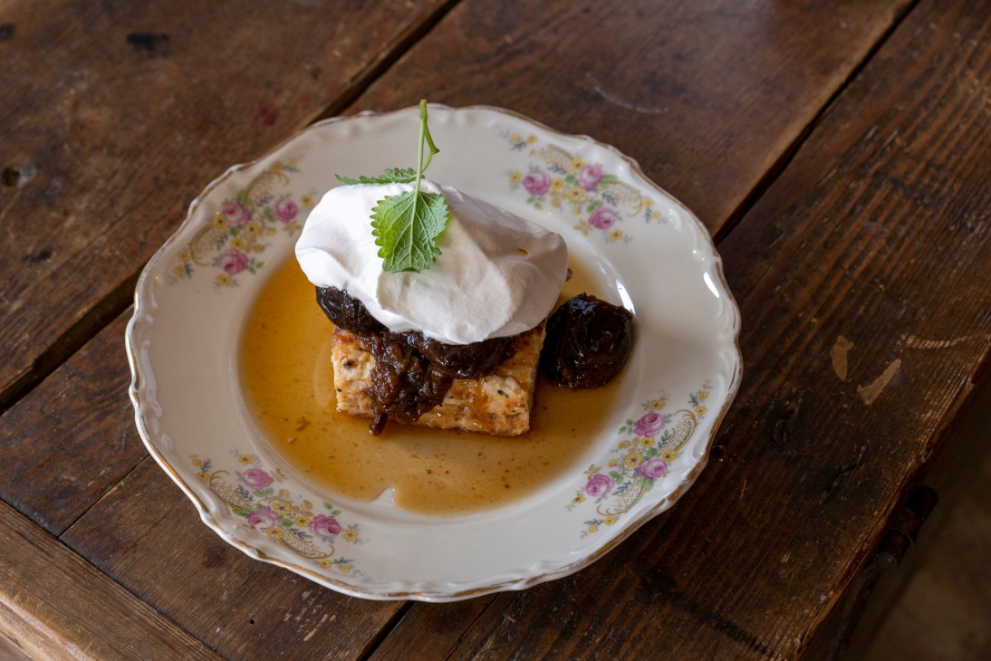 Dessert with whipped cream, dark berries and caramel sauce served on floral china plate