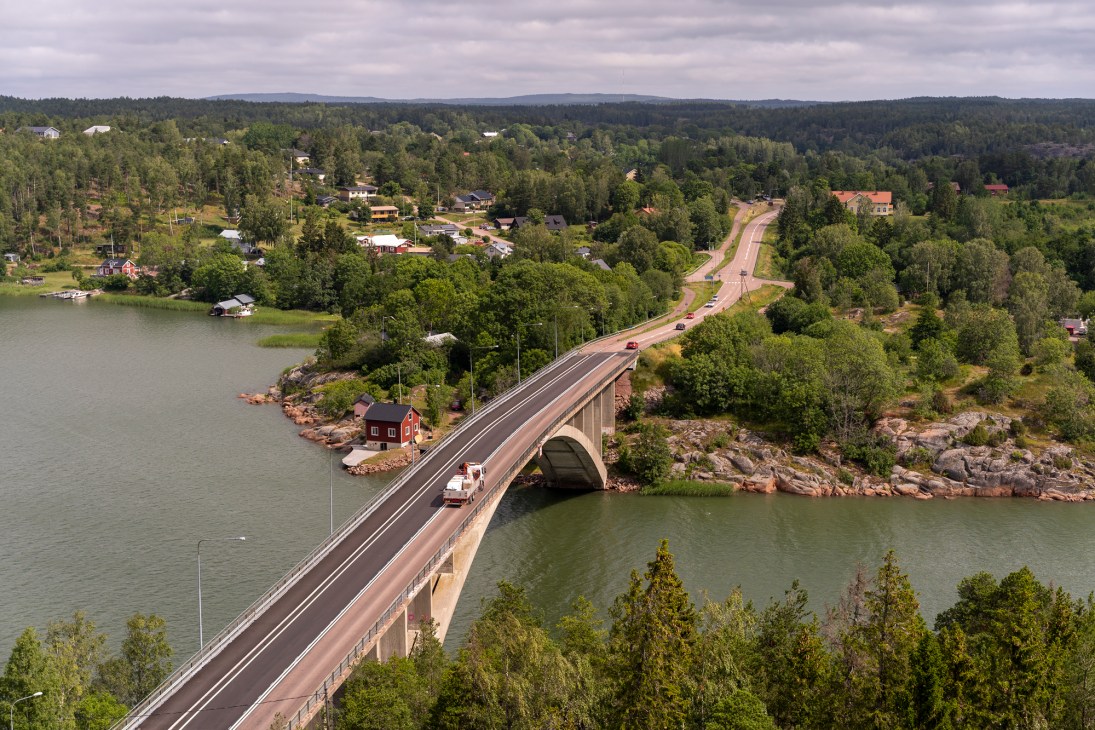 Modern concrete bridge with arch spanning across water channel connecting forested islands