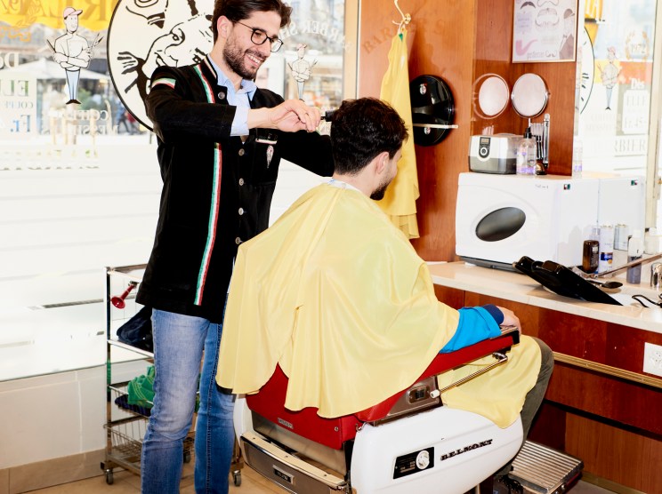 Fabio Palermo cutting a client's hair at his barber station in a modern barbershop