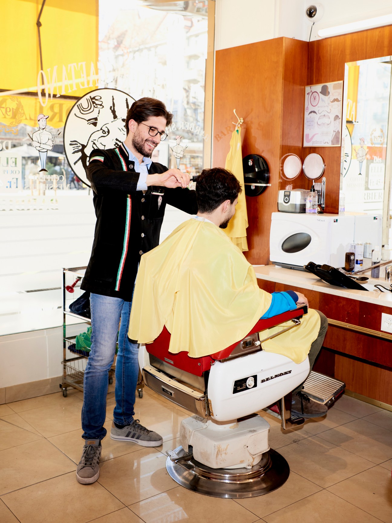 Fabio Palermo cutting a client's hair at his barber station in a modern barbershop