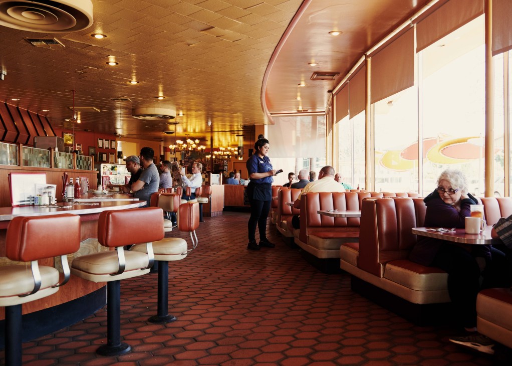 Interior of Bob's Big Boy diner with red vinyl banquettes, curved ceiling, and customers dining.