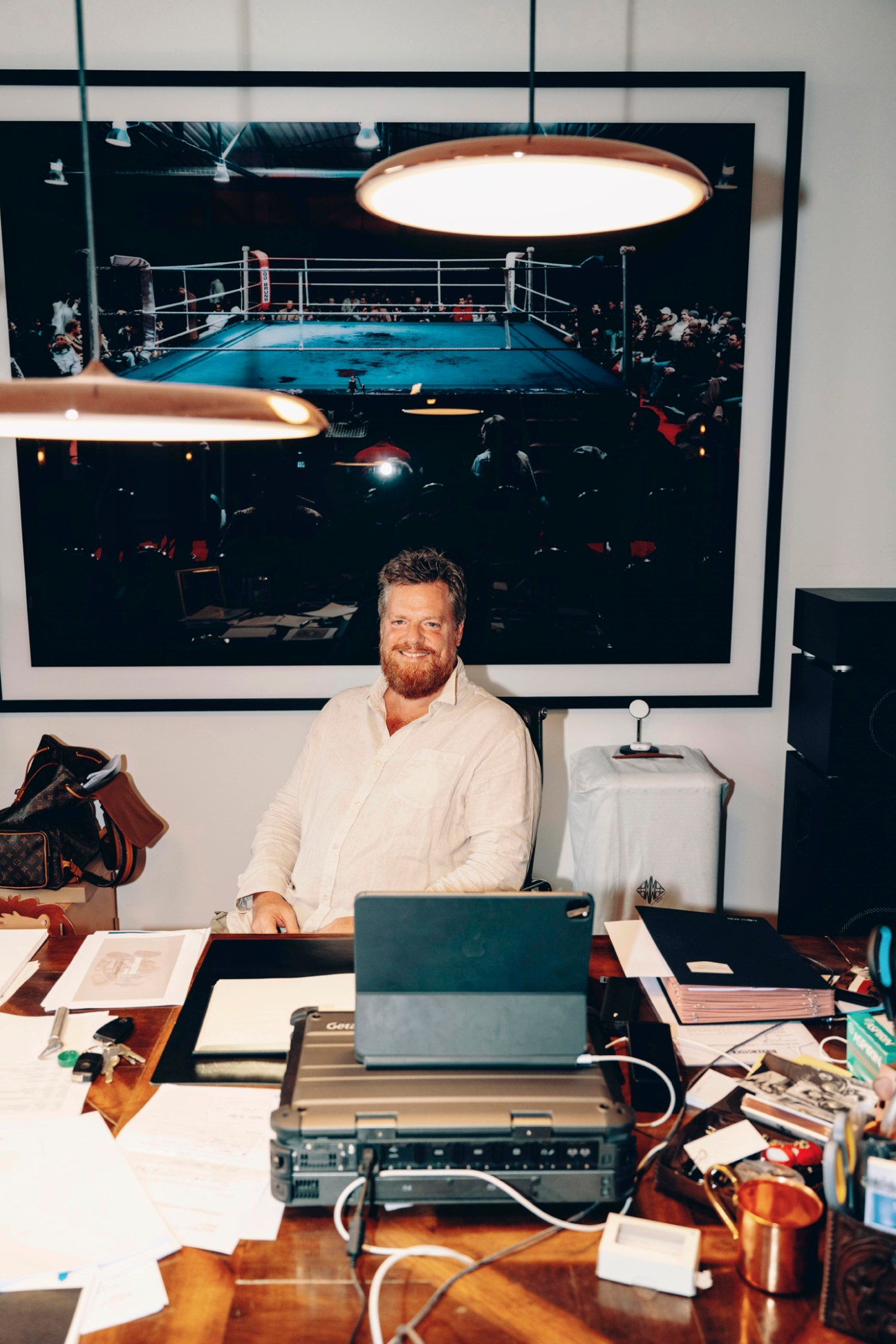 Oliver Reichert sits at his desk in his Munich office with a boxing ring photograph on the wall behind him