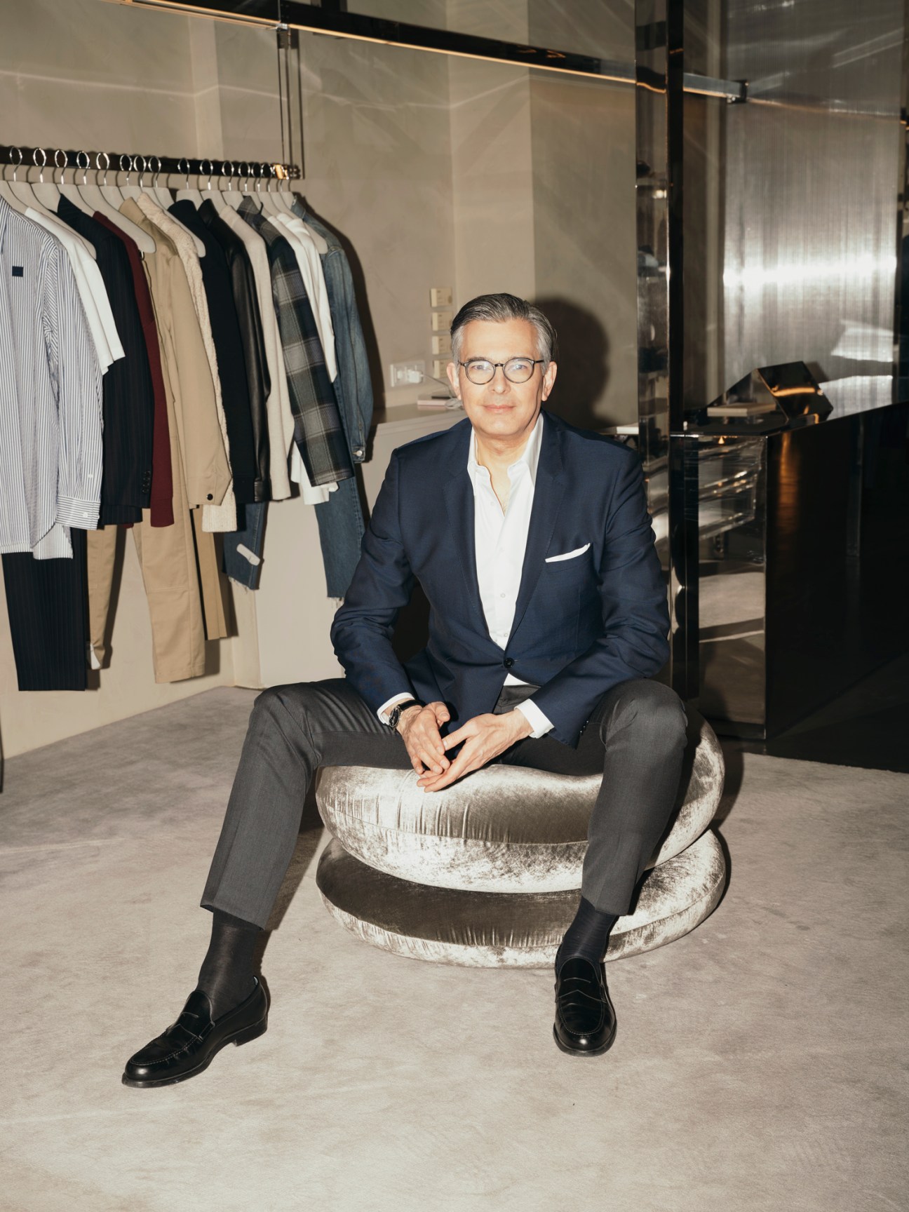 Michael Kliger, CEO of Mytheresa, sitting in a modern office with clothing racks and glass walls