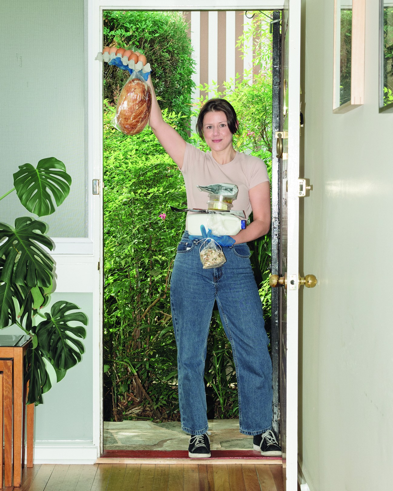 Woman in doorway holding delivered food packages in her hands.