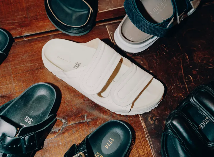 Various Birkenstock sandals and shoes arranged on a wooden floor showing different styles and colors