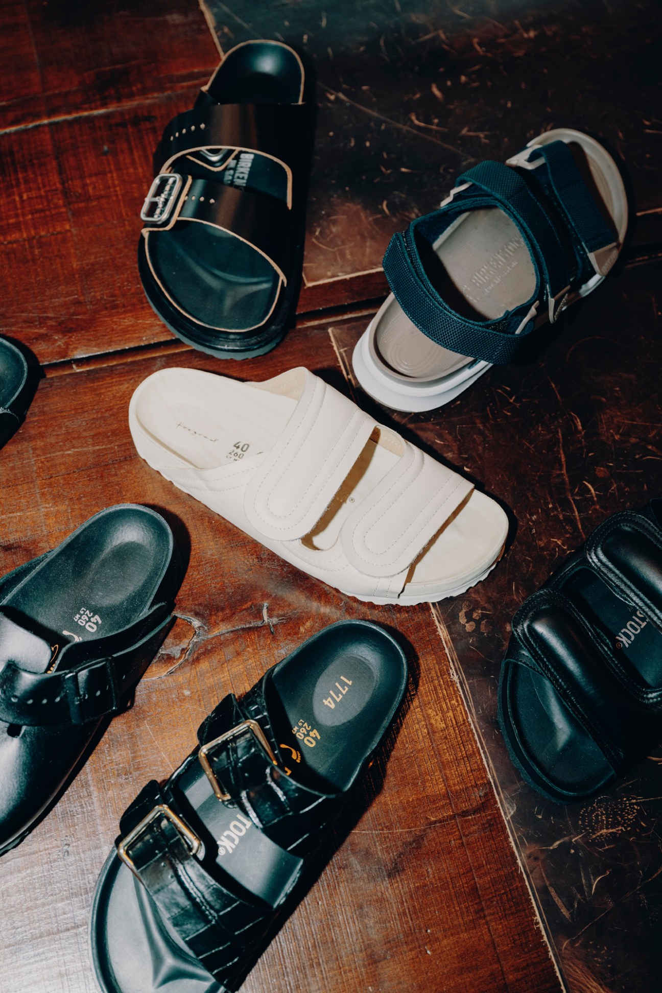 Various Birkenstock sandals and shoes arranged on a wooden floor showing different styles and colors