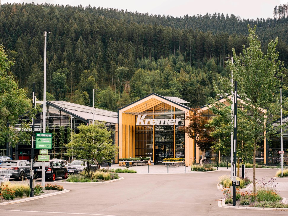 Kremer garden centre in Lennestadt with wooden facade and glass structure surrounded by forest.
