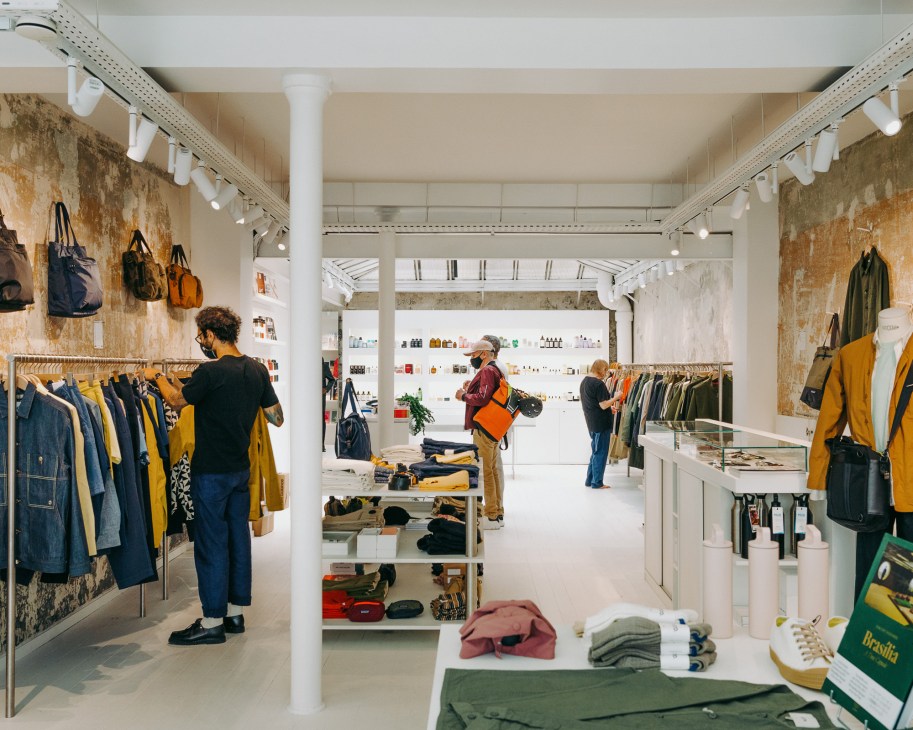 Centre Commercial Paris shop interior with customers browsing clothing racks and merchandise displays.