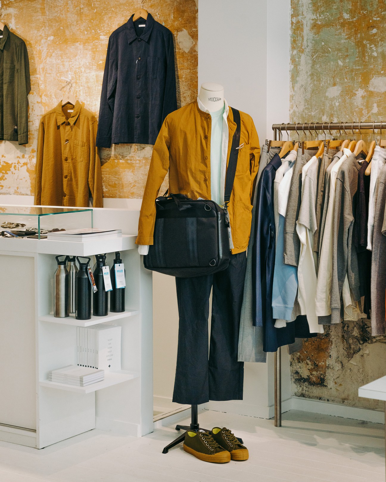 Fashion display at Centre Commercial Paris showing styled outfit on mannequin with clothing racks and distressed wall backdrop.