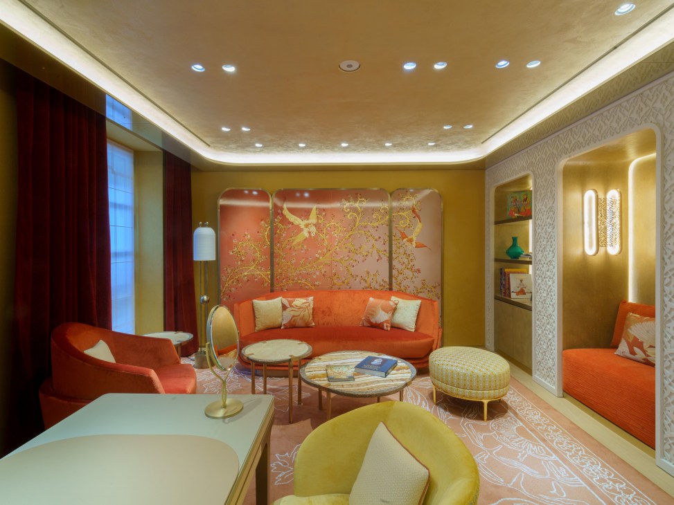 Intimate lounge area with curved orange sofa, cherry blossom artwork, and warm lighting in Cartier's renovated boutique