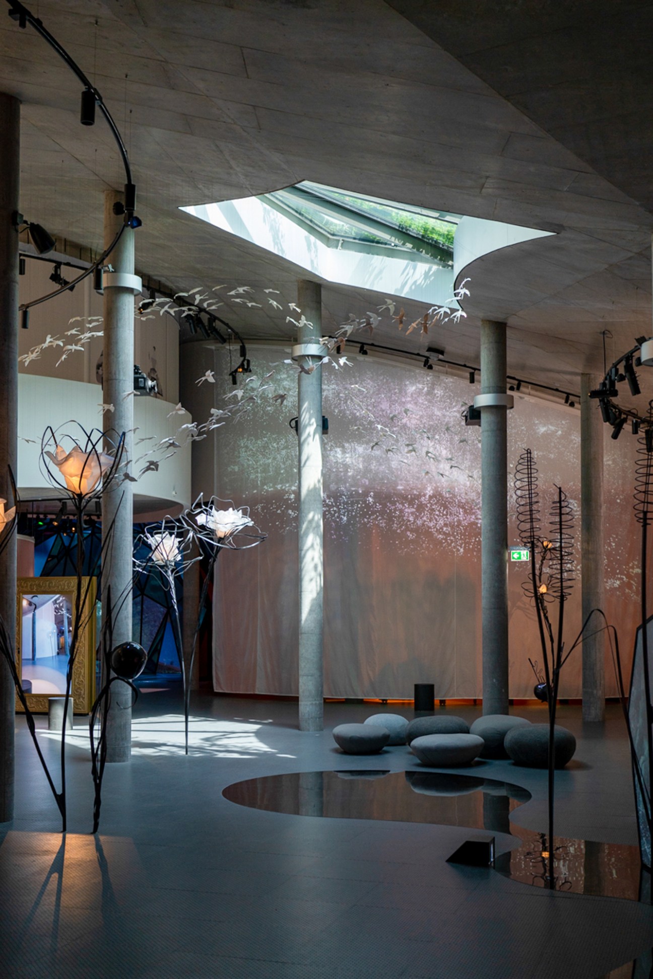 Modern museum interior with concrete ceiling, projections, sculptural installations and floor cushions