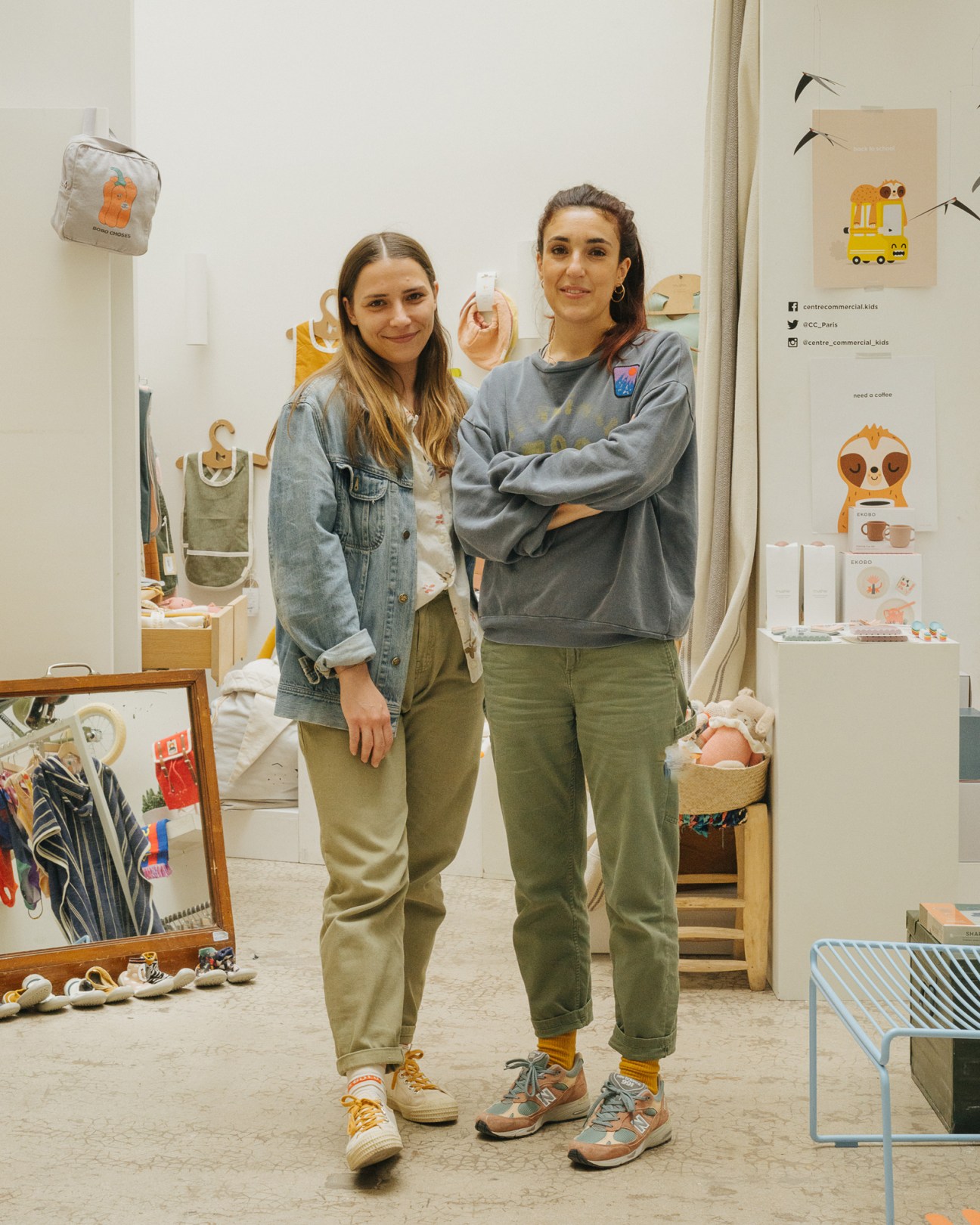 Two female staff members standing in Centre Commercial Kids shop surrounded by children's products and orange-themed décor.