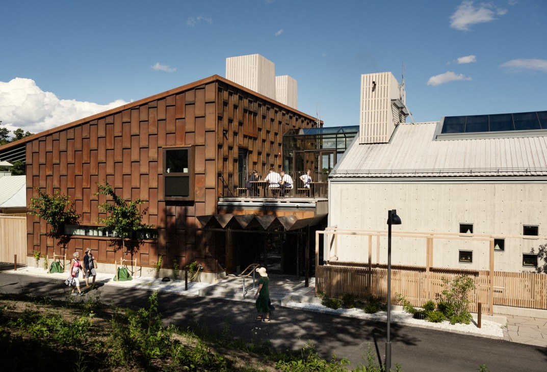 Modern restaurant building with brick facade, concrete structure and wooden terrace overlooking water