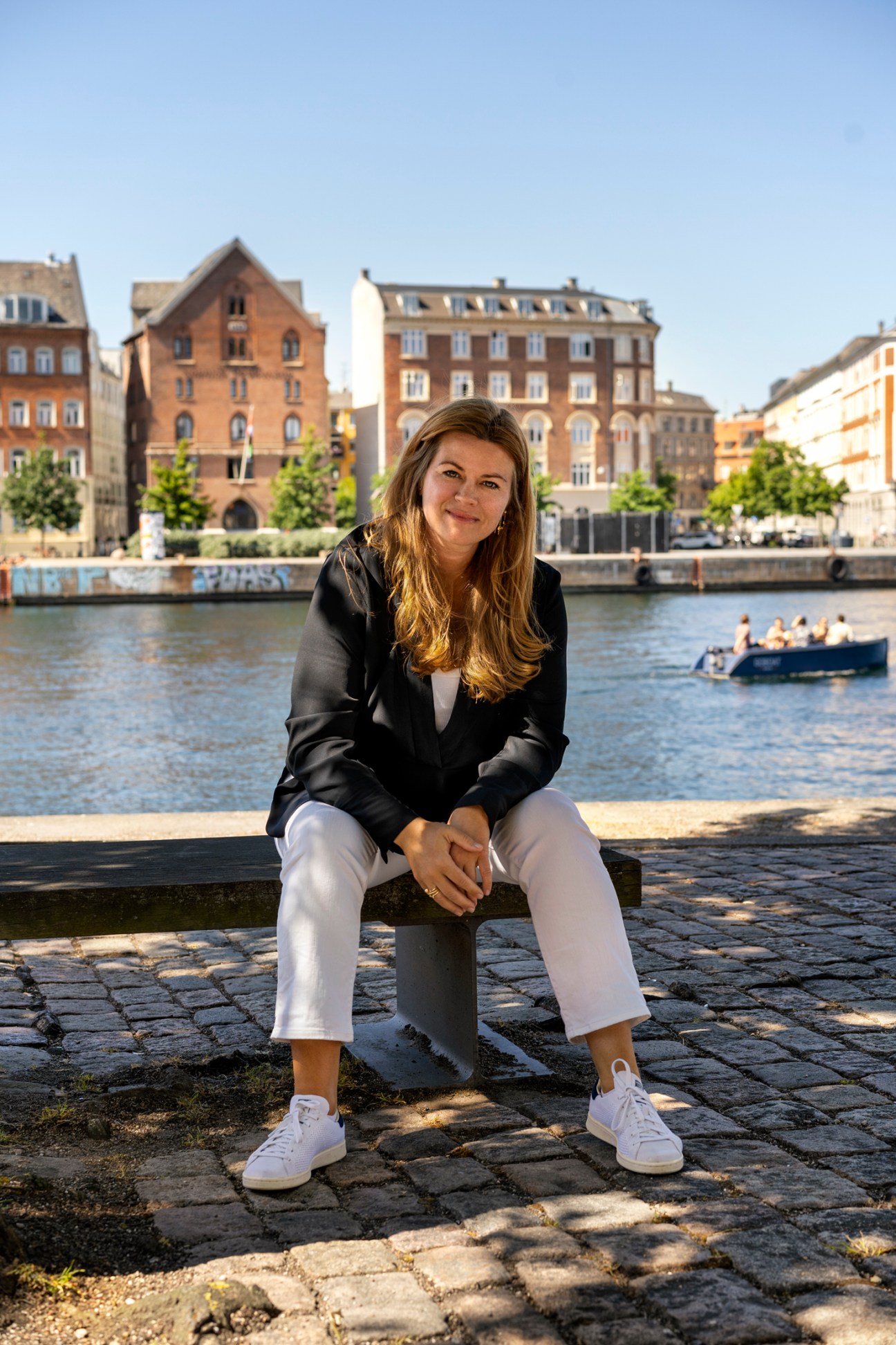 Camilla van Deurs, Copenhagen's city architect, sitting by waterfront with historic buildings in background